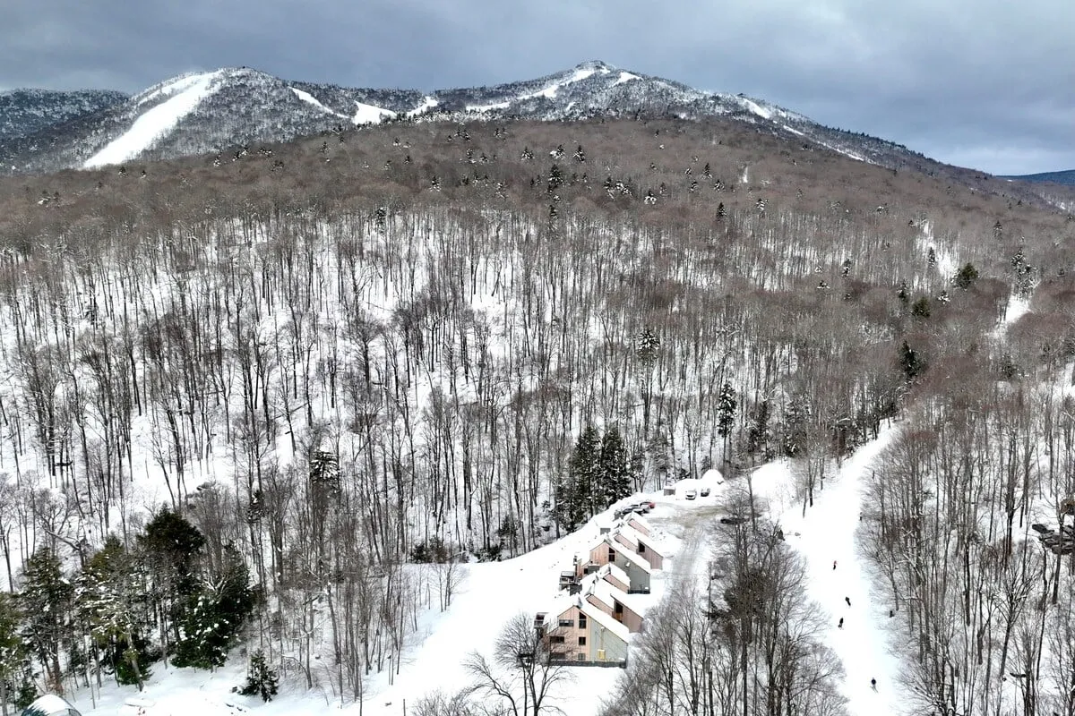 An inviting winter scene of snow-covered mountains, cozy cabins, and a snowy forest. The landscape evokes thoughts of après-ski relaxation, watching sunsets, and cozy evenings after outdoor adventures.