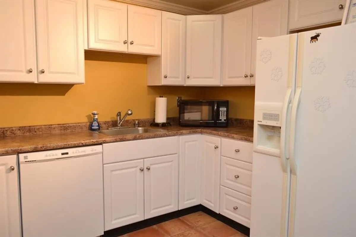 This image presents a modern kitchen featuring sleek appliances, spacious countertops, and cabinetry. The setup is inviting and functional, clearly designed for meal preparation and socializing, with enough space to move around comfortably.